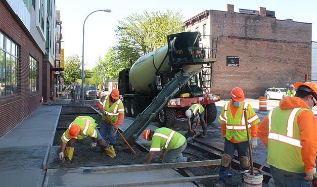 workers in safety gear pouring concrete