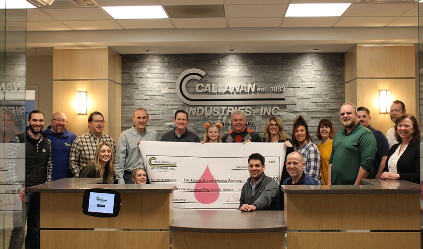 group of people behind counter holding a large check